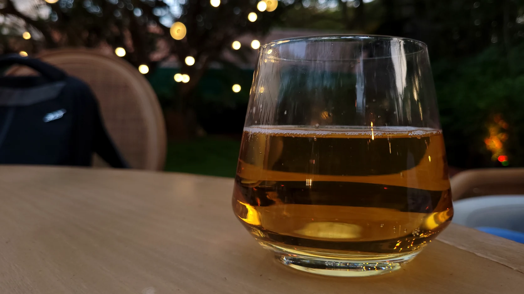 Real photo of natural amber colored whisky in a glass on an outdoor table